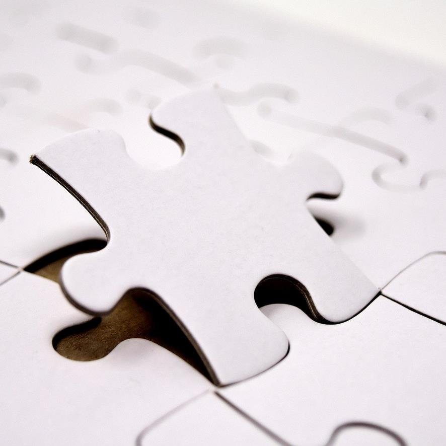 weißes Puzzle, das letzte Teil ist noch nicht ganz eingesetzt